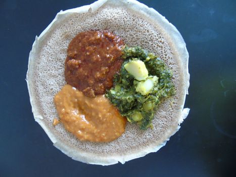 Asmara, Eritrea - 08/05/2020: Ethiopian and Eritrean food, assortment of main dishes. Injera is a sourdough flatbread made from teff flour. It is the national dish of Ethiopia, Eritrea.