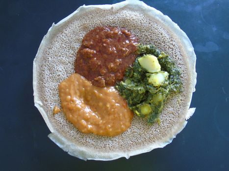 Asmara, Eritrea - 08/05/2020: Ethiopian and Eritrean food, assortment of main dishes. Injera is a sourdough flatbread made from teff flour. It is the national dish of Ethiopia, Eritrea.