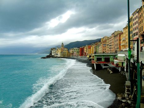 Liguria, Italy - 06/15/2020: Travelling around the ligurian seaside. Panoramic view to the seaside and the old villages. An amazing caption of the medieval coloured houses with grey sky in the background.