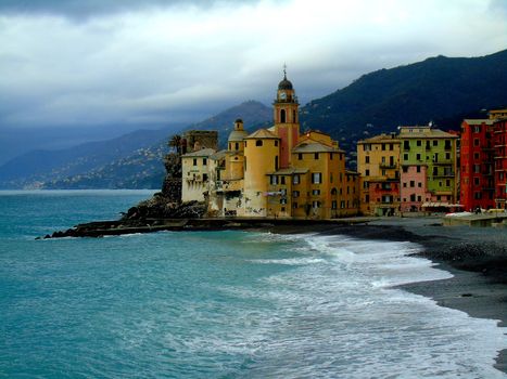 Liguria, Italy - 06/15/2020: Travelling around the ligurian seaside. Panoramic view to the seaside and the old villages. An amazing caption of the medieval coloured houses with grey sky in the background.