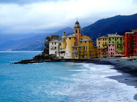 Liguria, Italy - 06/15/2020: Travelling around the ligurian seaside. Panoramic view to the seaside and the old villages. An amazing caption of the medieval coloured houses with grey sky in the background.