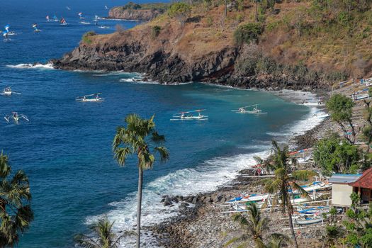 BALI, INDONESIA - JULY 29, 2019: A fisherman in traditional sailing jukung outrigger canoe returning with his catch to Amed, Japanese Wreck beach in Bali, Indonesia.