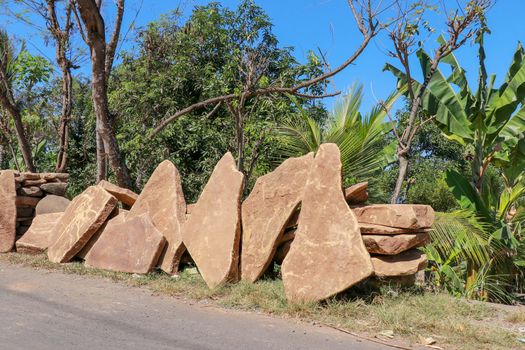 Big flat stones of yellow color for pathway. Natural building material. Boulders stacked on top of each other and ready for sale. Huge heavy stones.