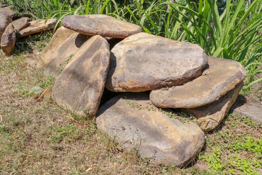 Big flat stones of yellow color for pathway. Natural building material. Boulders stacked on top of each other and ready for sale. Huge heavy stones.