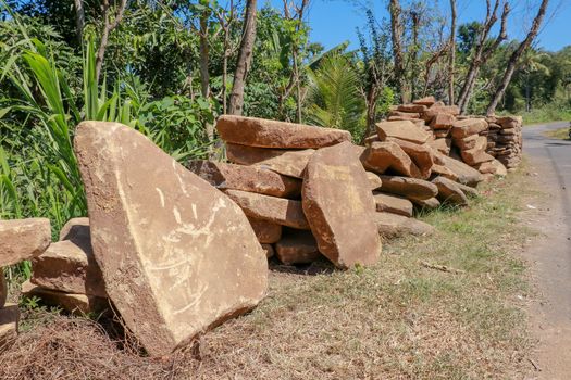 Big flat stones of yellow color for pathway. Natural building material. Boulders stacked on top of each other and ready for sale. Huge heavy stones.