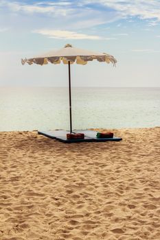 Beautiful sandy beach with umbrella, mattress and pillow