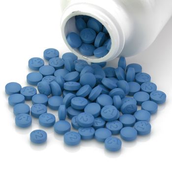 A pile of blue pills and medication bottle