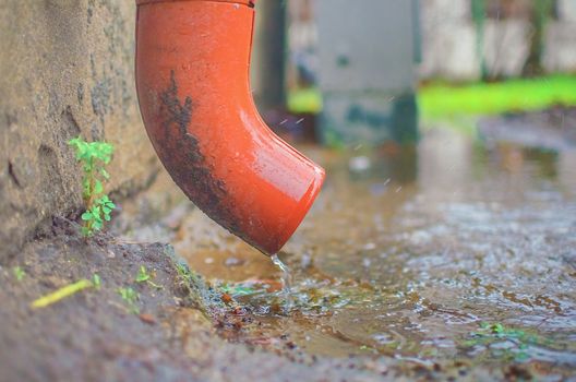 Rain water flowing from metal downspout during a flood. concept of protection against heavy downpours.