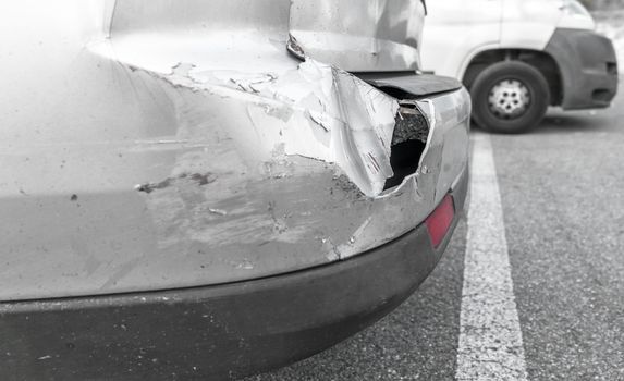 Back of gray car get damaged from accident on the road. Vehicle bumper dent broken by car crash. Road accidents.