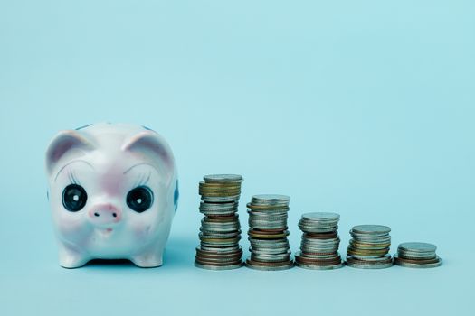 Saving piggy bank with step of money coins on blue background for investment, business, finance and saving money concept