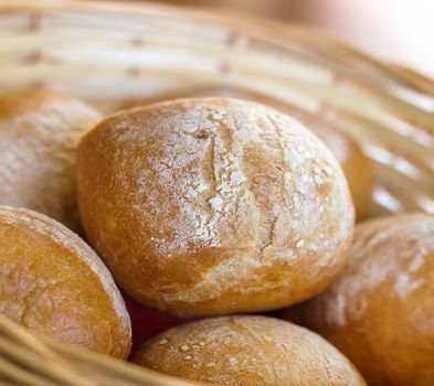 Close up of wicker filled with buns. Fresh bakery products on table. Shallow DOF.