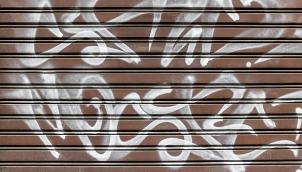 Garage gate with vandalism sign of graffiti white spray paint. Ideal for concepts and backgrounds.