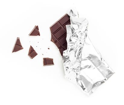 Chocolate Bar Tablet Wrapped in Aluminum Foil isolated over white Background. Some pieces are scattered around. Ideal for concepts.