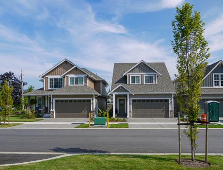 New family houses with concrete driveway and asphalt road in front. Brand new houses for sale