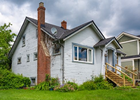 Old residential house with brick chimney neglected lawn on the front yard