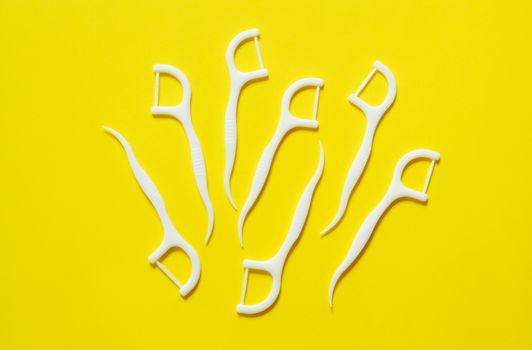 Dental floss, white color toothpick. Isolated on yellow background.