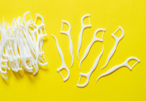 Dental floss, toothpick, oral cleaning device. Isolated on yellow background.