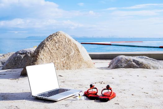 Laptop computer and shoes on the beach. work and travel in summer.