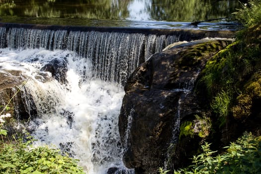 A small waterfall off an old powerplant dam, in the forest