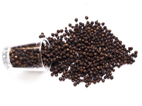 Dried black pepper seeds, peppercorn in a clear glass isolated on white background