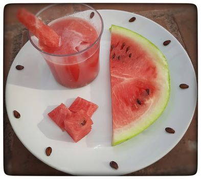 Chill watermelon juice with cut pieces and ice cubes and slices of watermelon in white plate and good for summer days and healthy fruit