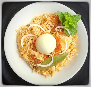 Colorful Delicious yummy egg rice with egg in center with indian spicy mushroom gravy beautifully in black bowl and it's one of favorite restaurant cuisine food