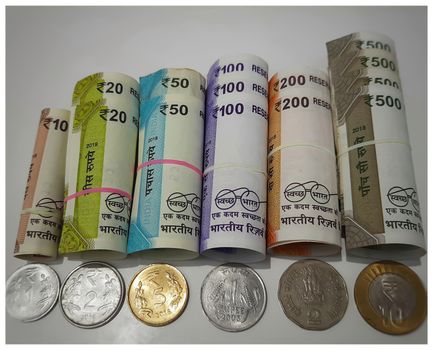 New Indian rupees currency notes rolls with rubber band randomly with rupees coins in white paper