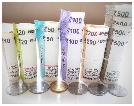 New Indian rupees currency notes rolls with rubber band randomly with rupees coins in white paper