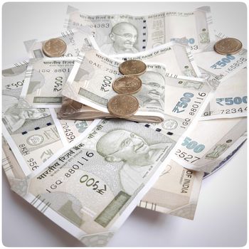 Indian new 500 rupees currency notes spread randomly with 5 rupee coins in white paper