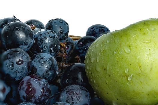 Bright purple grapes and green apples in a wooden basket on a white background.