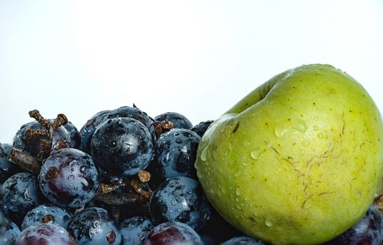 Bright purple grapes and green apples in a wooden basket on a white background.