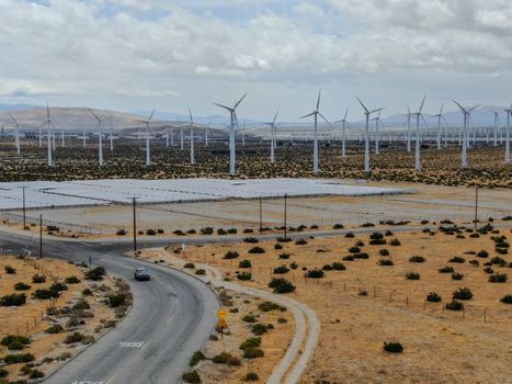 Aerial view of huge array of gigantic wind turbines spreading over the desert in Palm Springs wind farm. California. USA. Aerial view of wind turbines generating electricity. 