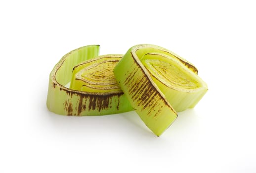 Isolated pieces of roasted green leek on the white background