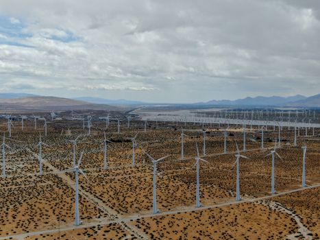 Aerial view of huge array of gigantic wind turbines spreading over the desert in Palm Springs wind farm. California. USA. Aerial view of wind turbines generating electricity. 