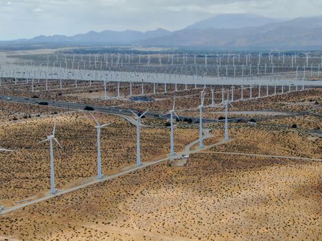 Aerial view of huge array of gigantic wind turbines spreading over the desert in Palm Springs wind farm. California. USA. Aerial view of wind turbines generating electricity. 