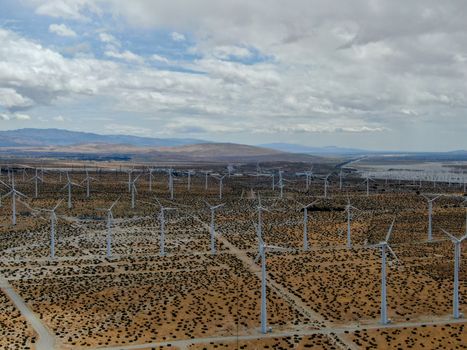 Aerial view of huge array of gigantic wind turbines spreading over the desert in Palm Springs wind farm. California. USA. Aerial view of wind turbines generating electricity. 