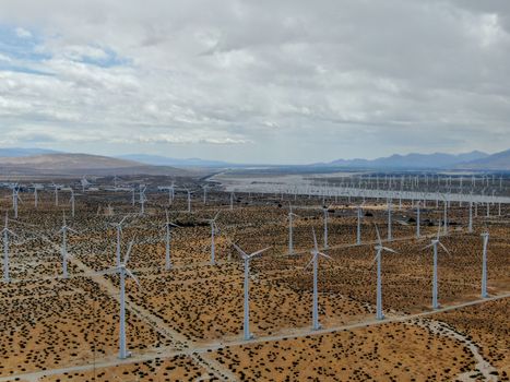 Aerial view of huge array of gigantic wind turbines spreading over the desert in Palm Springs wind farm. California. USA. Aerial view of wind turbines generating electricity. 