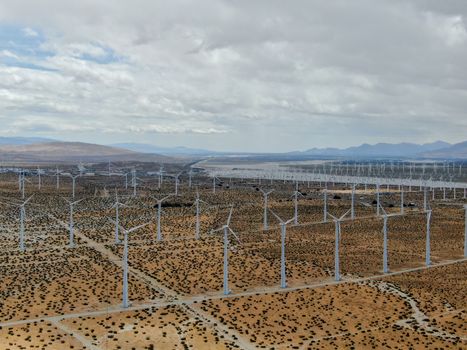 Aerial view of huge array of gigantic wind turbines spreading over the desert in Palm Springs wind farm. California. USA. Aerial view of wind turbines generating electricity. 