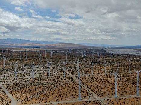 Aerial view of huge array of gigantic wind turbines spreading over the desert in Palm Springs wind farm. California. USA. Aerial view of wind turbines generating electricity. 