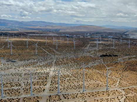 Aerial view of huge array of gigantic wind turbines spreading over the desert in Palm Springs wind farm. California. USA. Aerial view of wind turbines generating electricity. 