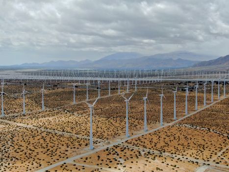 Aerial view of huge array of gigantic wind turbines spreading over the desert in Palm Springs wind farm. California. USA. Aerial view of wind turbines generating electricity. 