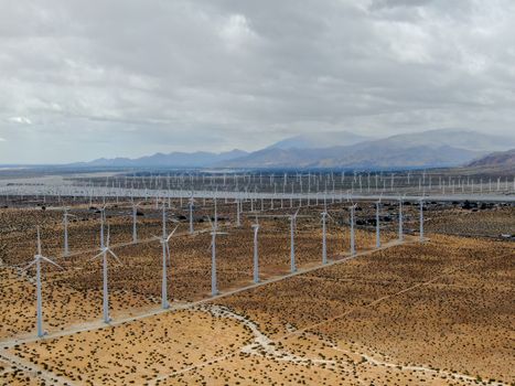 Aerial view of huge array of gigantic wind turbines spreading over the desert in Palm Springs wind farm. California. USA. Aerial view of wind turbines generating electricity. 