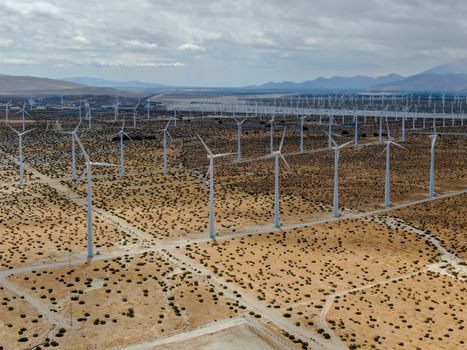 Aerial view of huge array of gigantic wind turbines spreading over the desert in Palm Springs wind farm. California. USA. Aerial view of wind turbines generating electricity. 