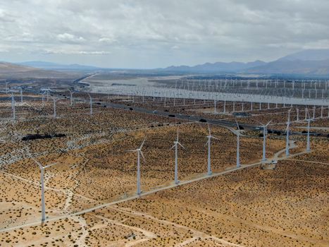 Aerial view of huge array of gigantic wind turbines spreading over the desert in Palm Springs wind farm. California. USA. Aerial view of wind turbines generating electricity. 