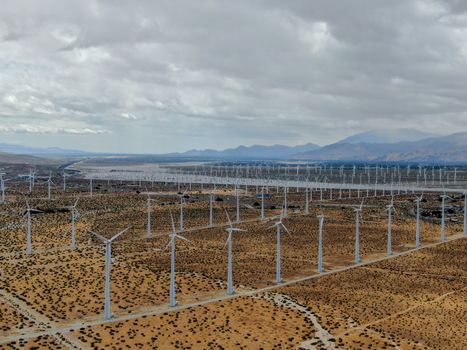 Aerial view of huge array of gigantic wind turbines spreading over the desert in Palm Springs wind farm. California. USA. Aerial view of wind turbines generating electricity. 