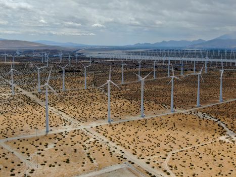 Aerial view of huge array of gigantic wind turbines spreading over the desert in Palm Springs wind farm. California. USA. Aerial view of wind turbines generating electricity. 