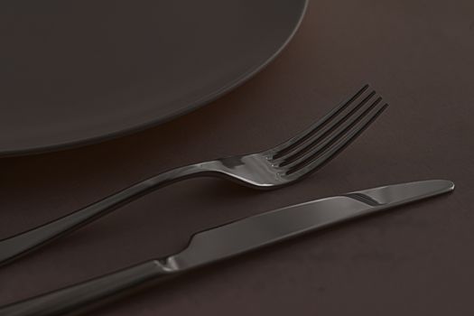 Empty plate and cutlery as mockup set on dark brown background, top tableware for chef table decor and menu branding design