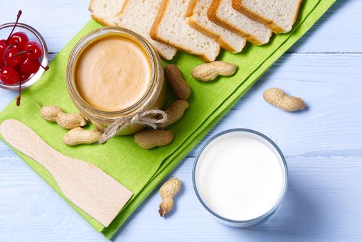 american breakfast milk and peanut butter. Peanut butter, white bread with glass of milk on blue wooden background