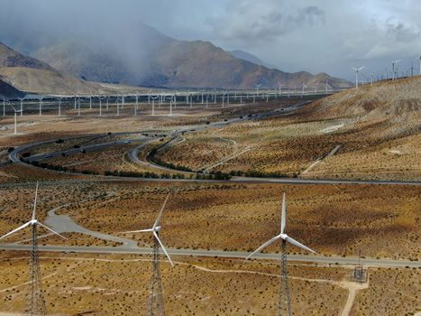 Aerial view of huge array of gigantic wind turbines spreading over the desert in Palm Springs wind farm. California. USA. Aerial view of wind turbines generating electricity. 