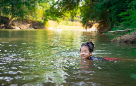 little asian girl playing in the river with sunlight